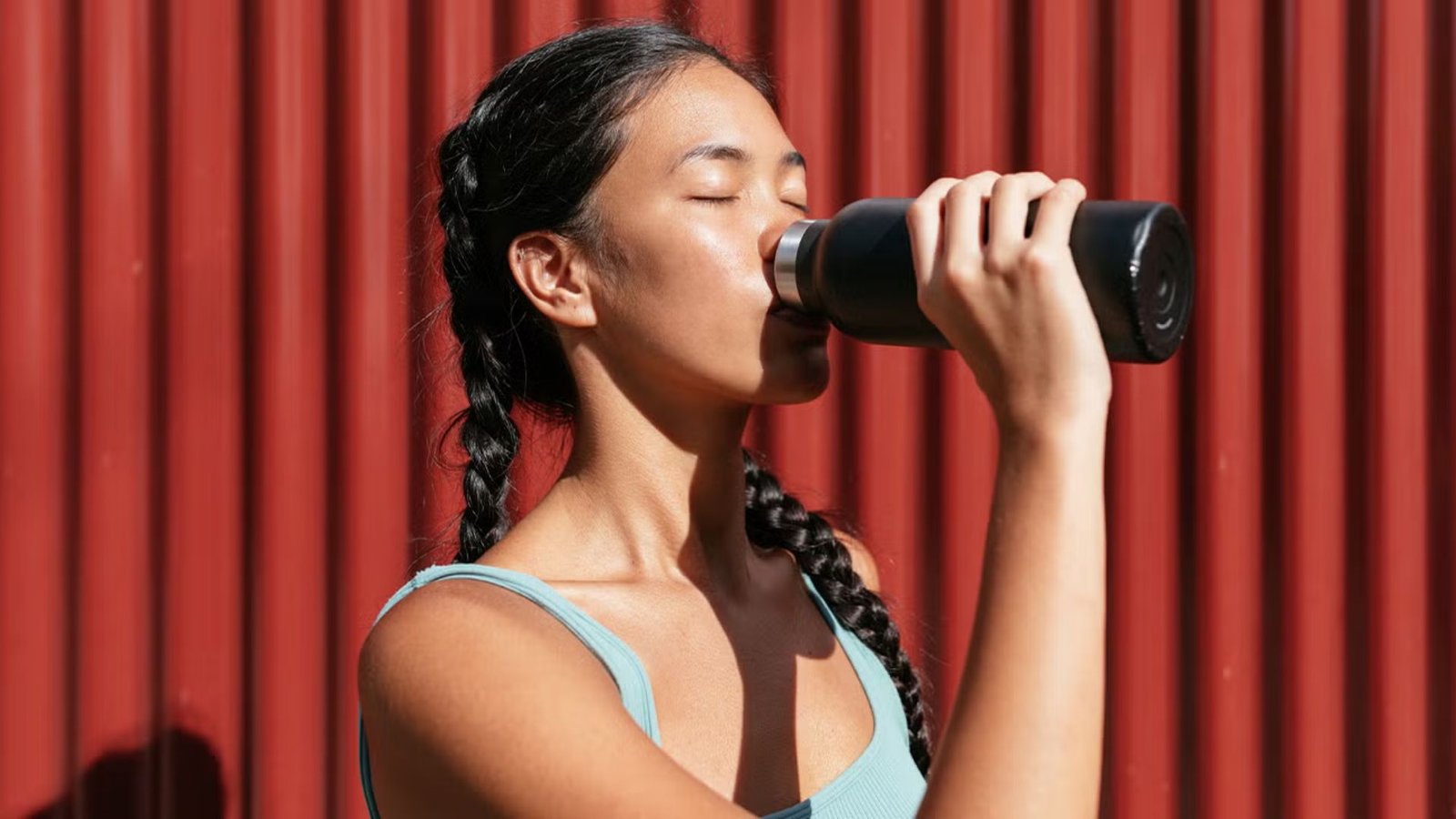 woman drinking water from a reusable bottle to stay hydrated during her fitness routine.