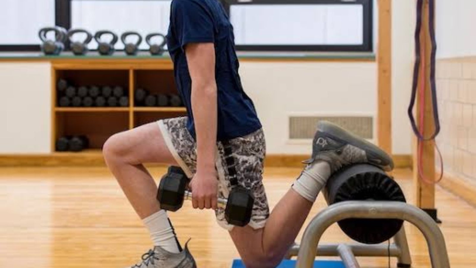 man performing a Bulgarian split squat with dumbbells to build quad strength and balance.