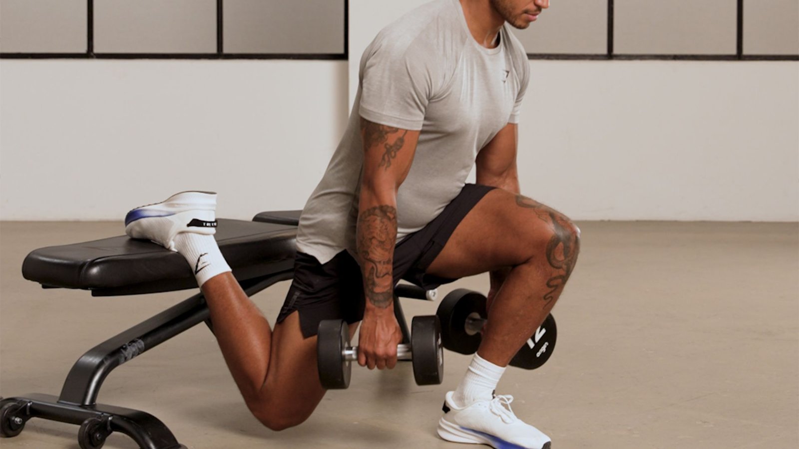 man doing a Bulgarian split squat with rear foot on a bench for single-leg quad strength.