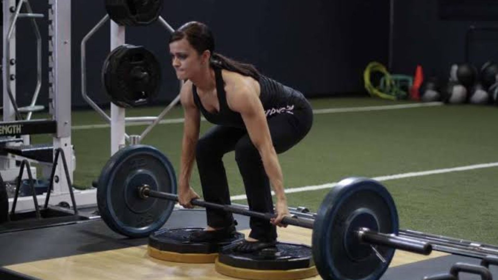 woman performing a deficit deadlift from a low platform.