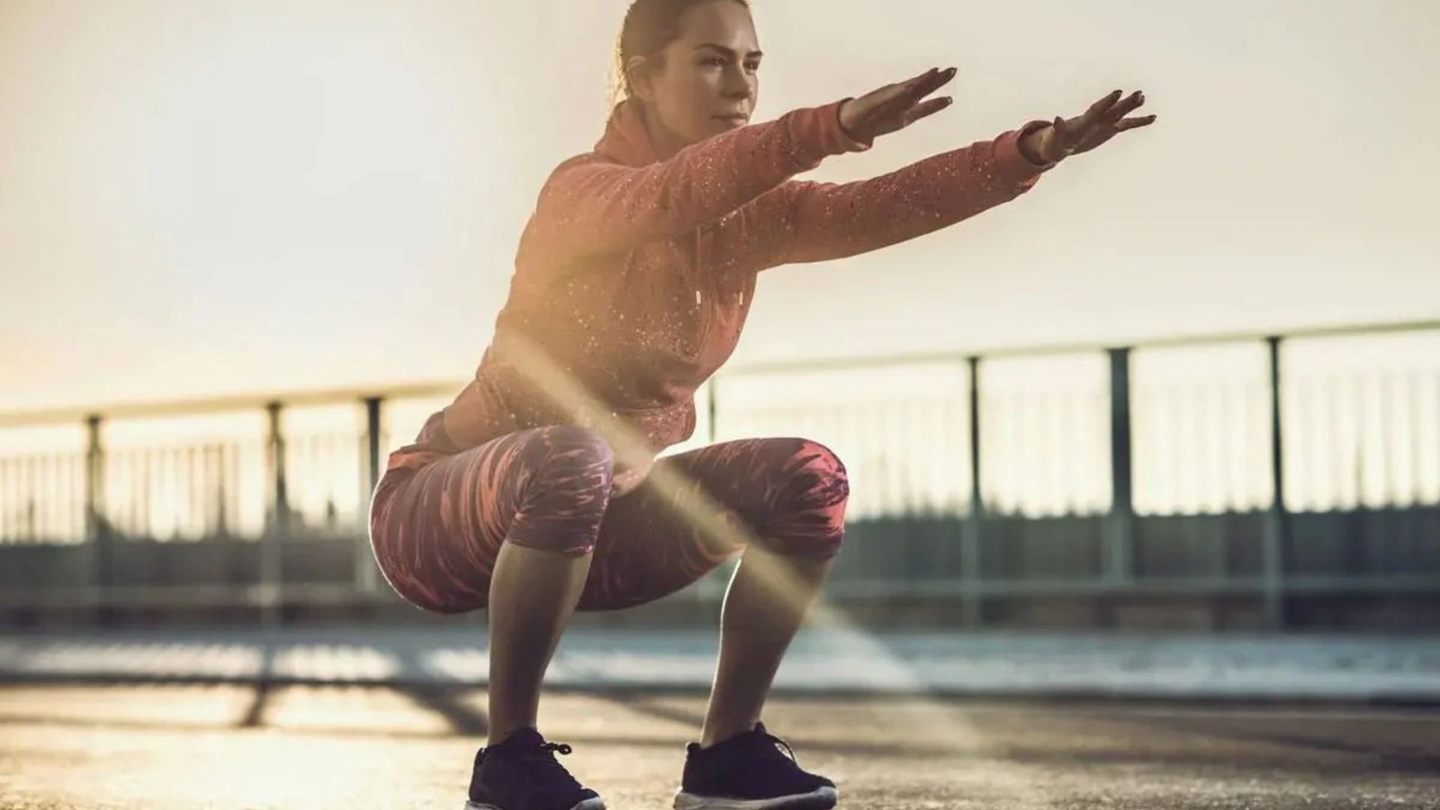 woman performing a deep squat outdoors to strengthen quads, improve knee stability, and build lower-body strength.
