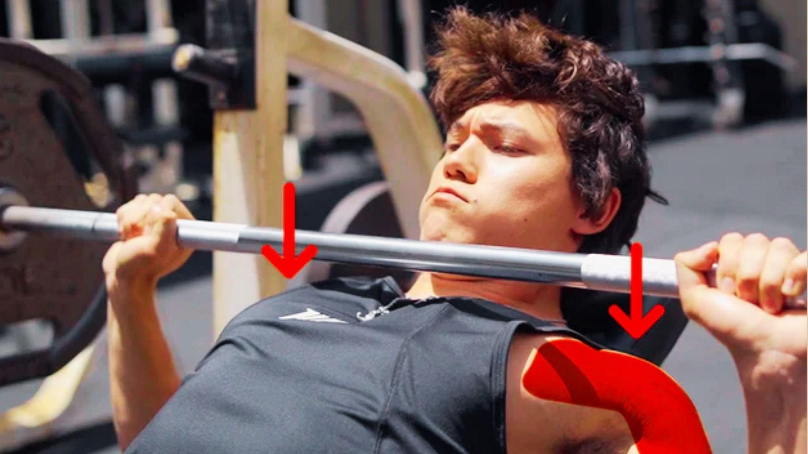 Young man bench pressing barbell with red down arrows and red highlighted front shoulder area.