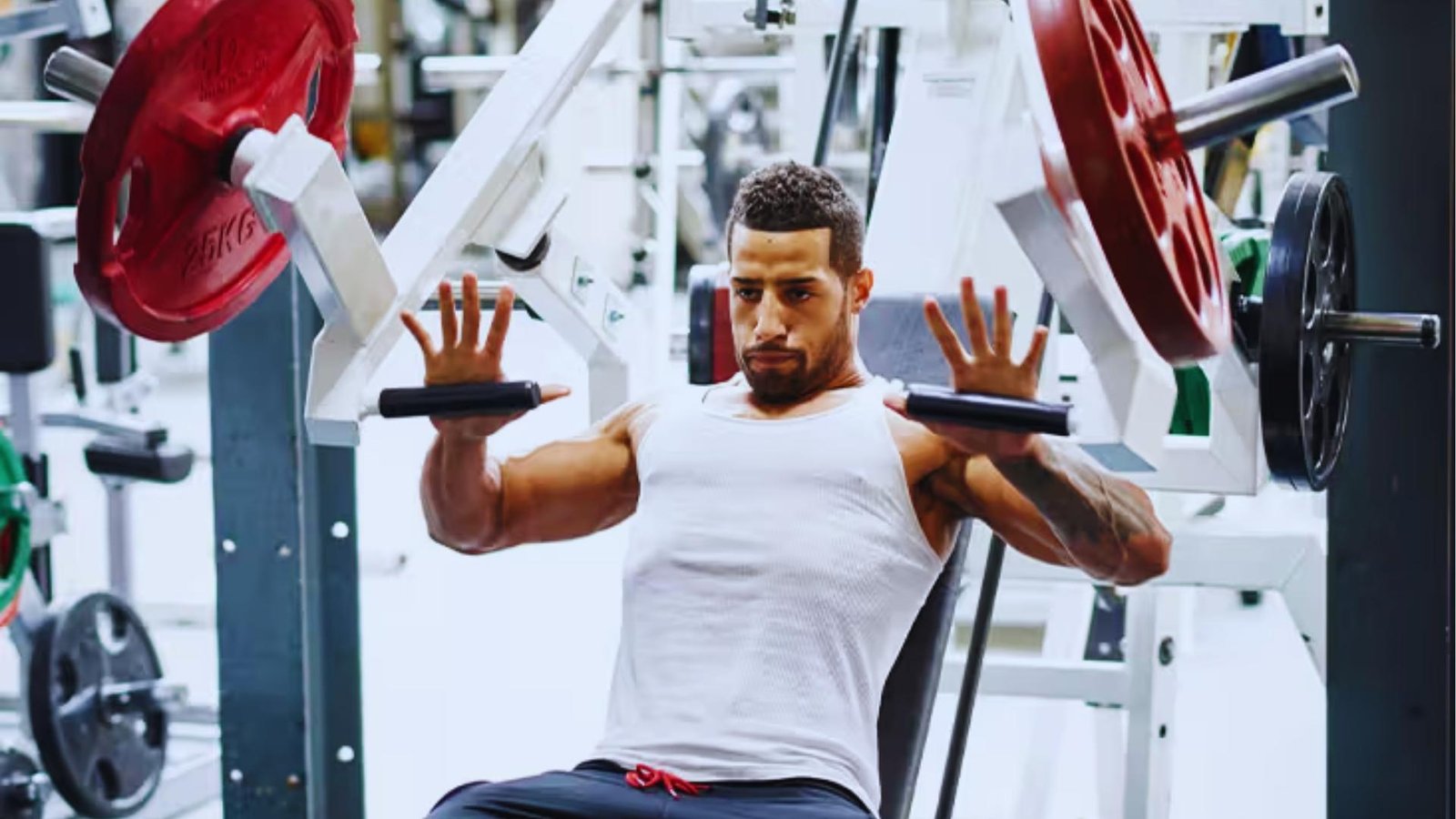 Man on chest press machine with open hands showing alternative to barbell bench to avoid shoulder pain.