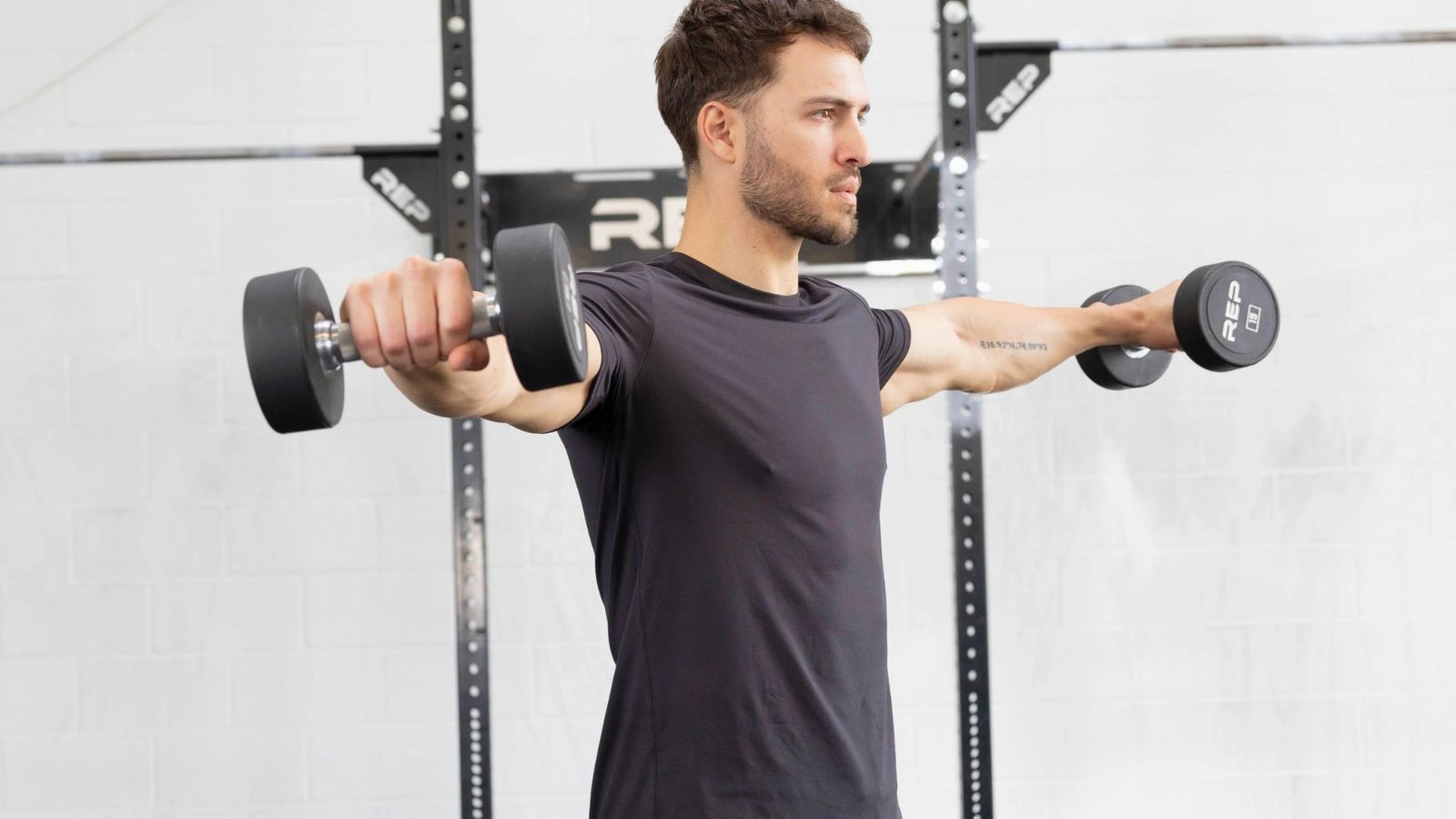 man performing dumbbell lateral raises with controlled form to target the side delts.