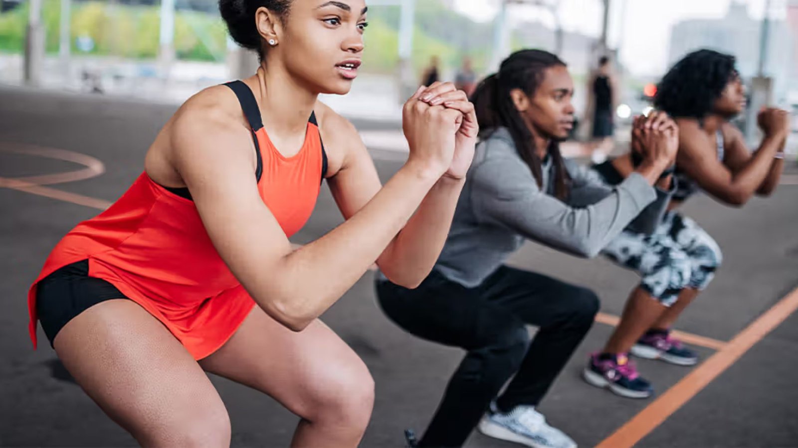 group of people performing bodyweight squats during an outdoor fitness workout session.