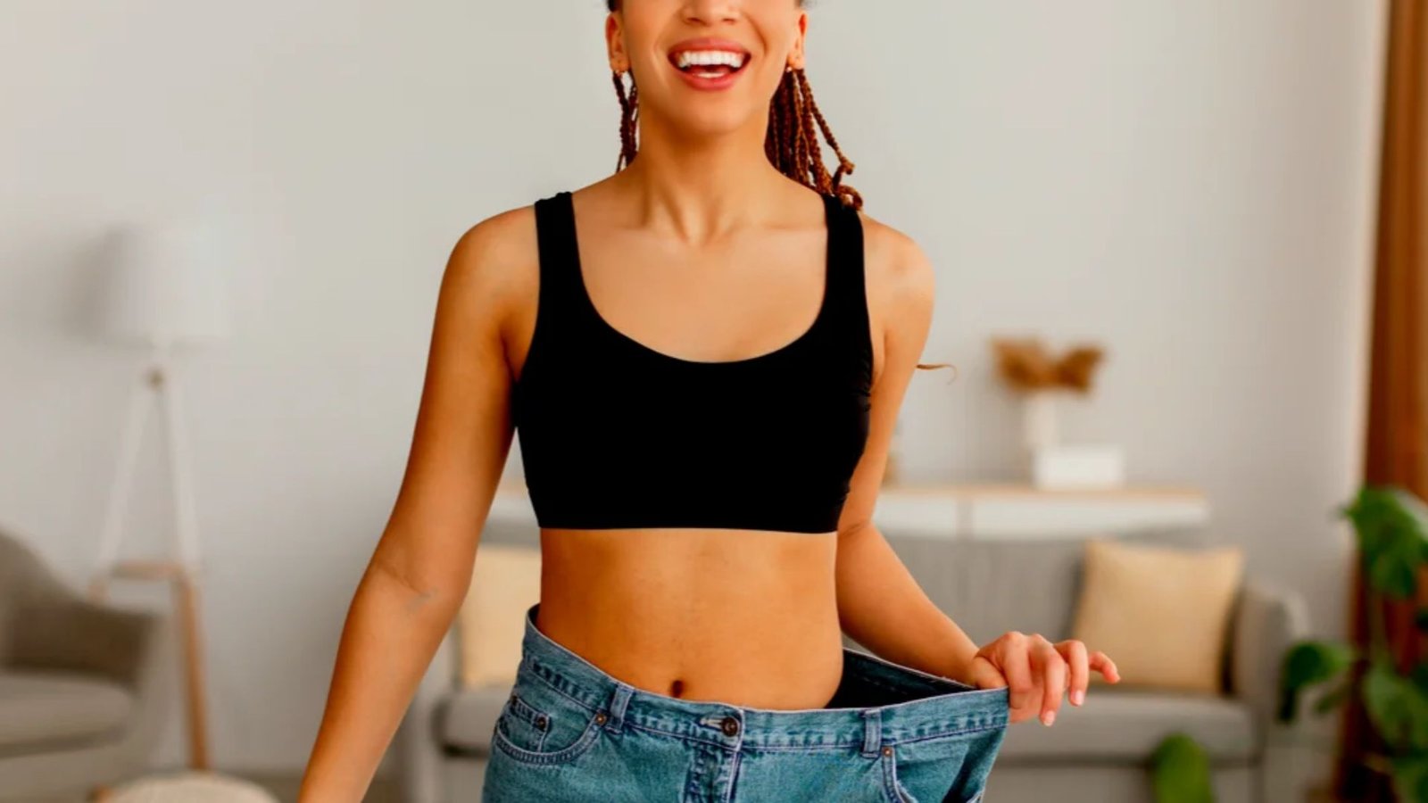 smiling woman wearing oversized jeans after successful weight loss in two months.