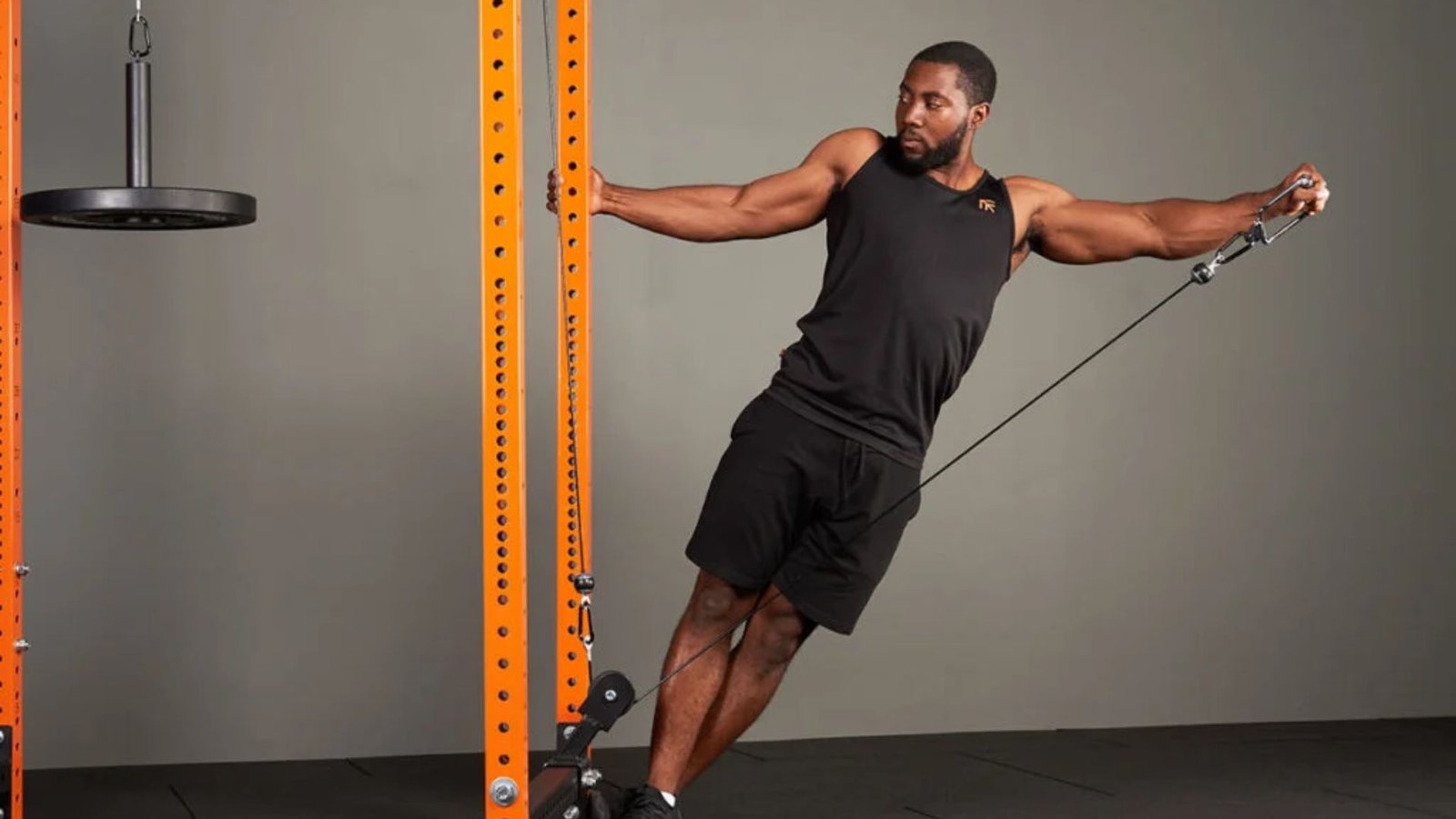 athlete doing a single-arm cable lateral raise to build wider and stronger shoulders.