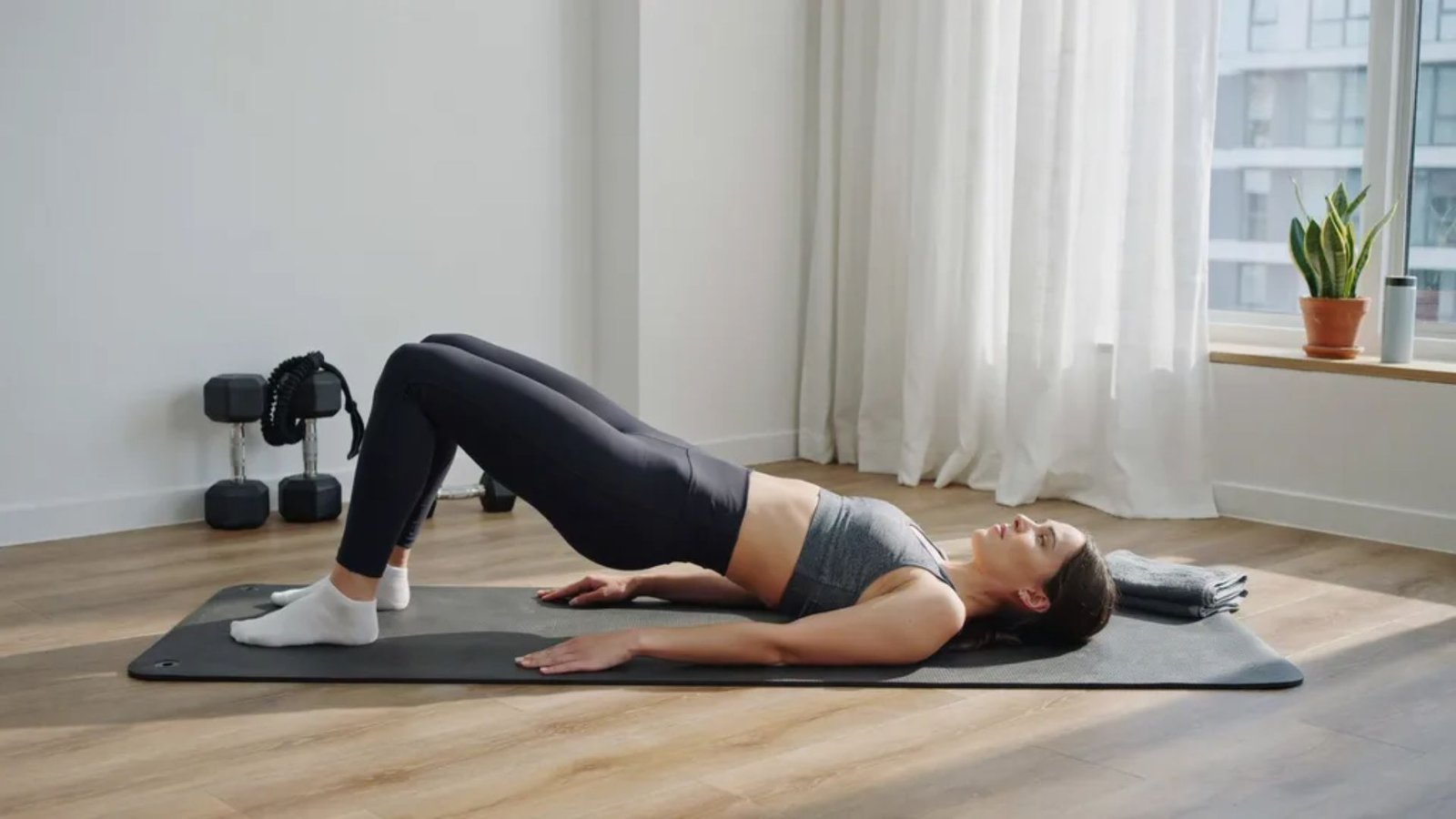 beginner performing a glute bridge with proper form on an exercise mat.
