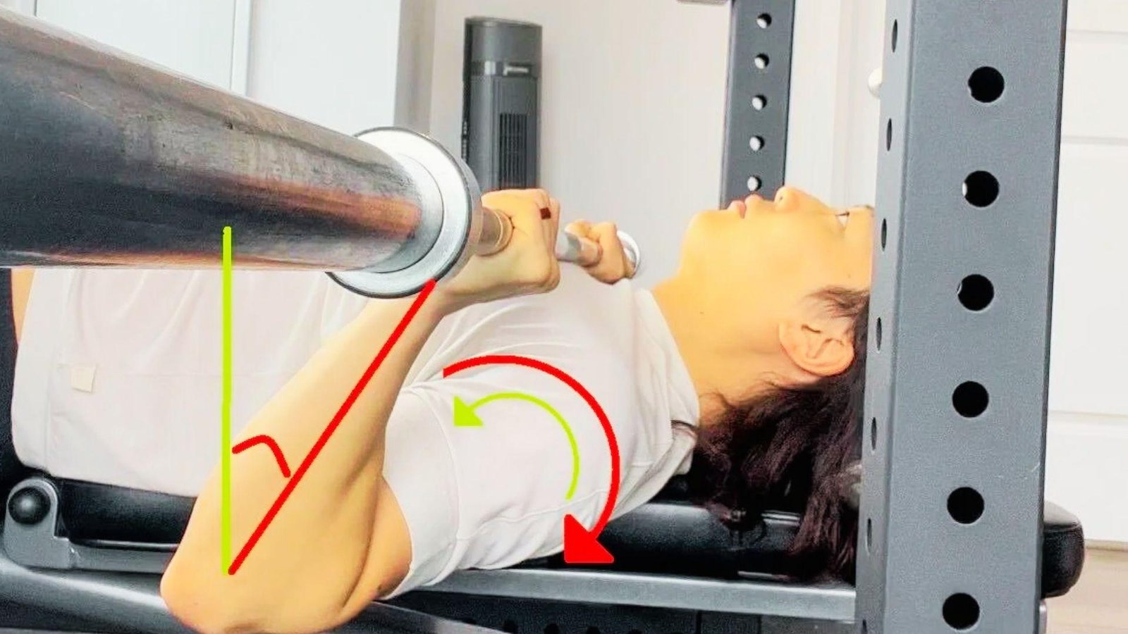 Person in white shirt bench pressing barbell with red and green angle and rotation arrows on shoulder.