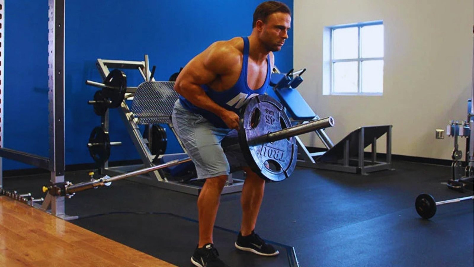 Man performing T-bar chest supported row with heavy plate in gym for back gains.