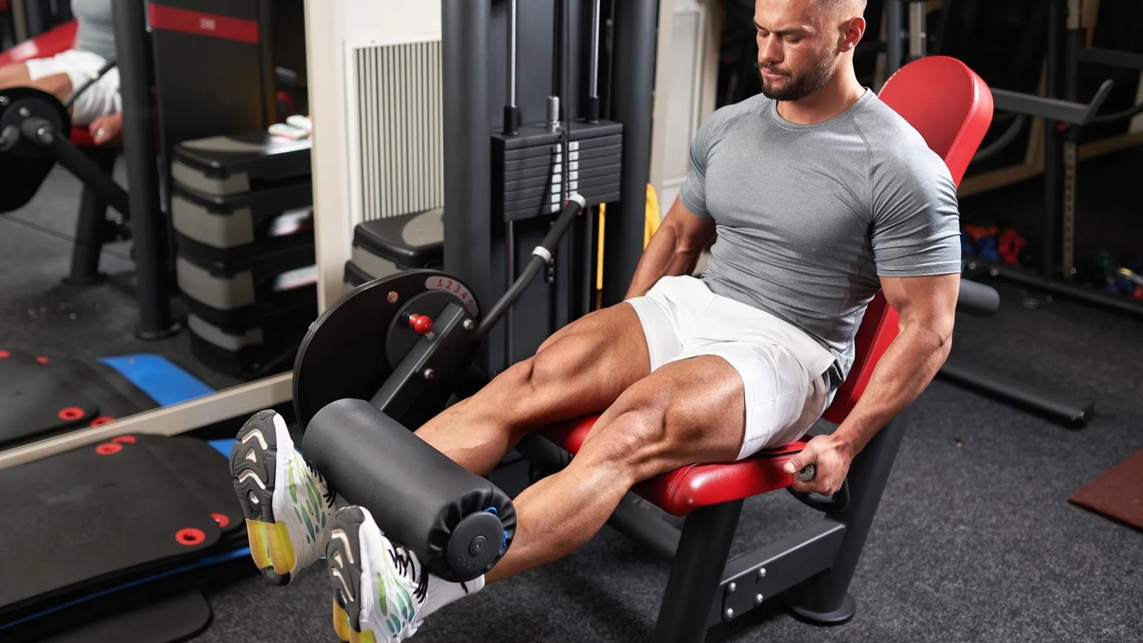 man performing leg extensions on a machine to isolate and strengthen the quadriceps.