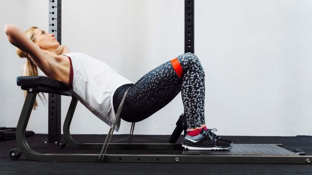 Person performing upper glute exercises using a hip thrust and resistance band.