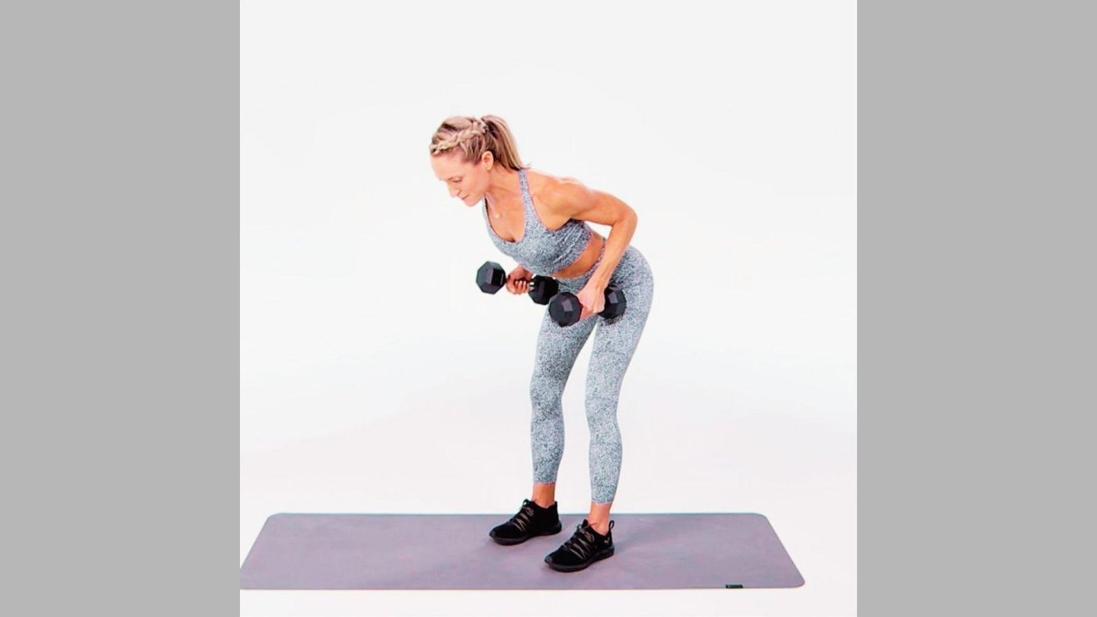 Woman in gray patterned workout set doing bent-over dumbbell rows on purple mat against white background.
