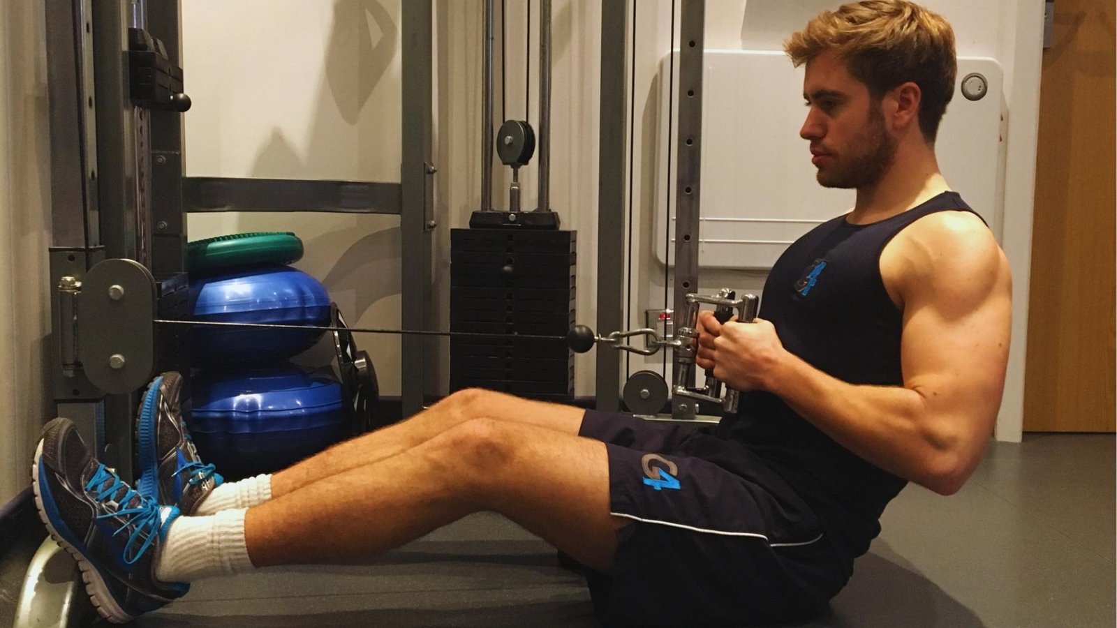Man doing seated cable chest supported row on low pulley machine, back exercise.