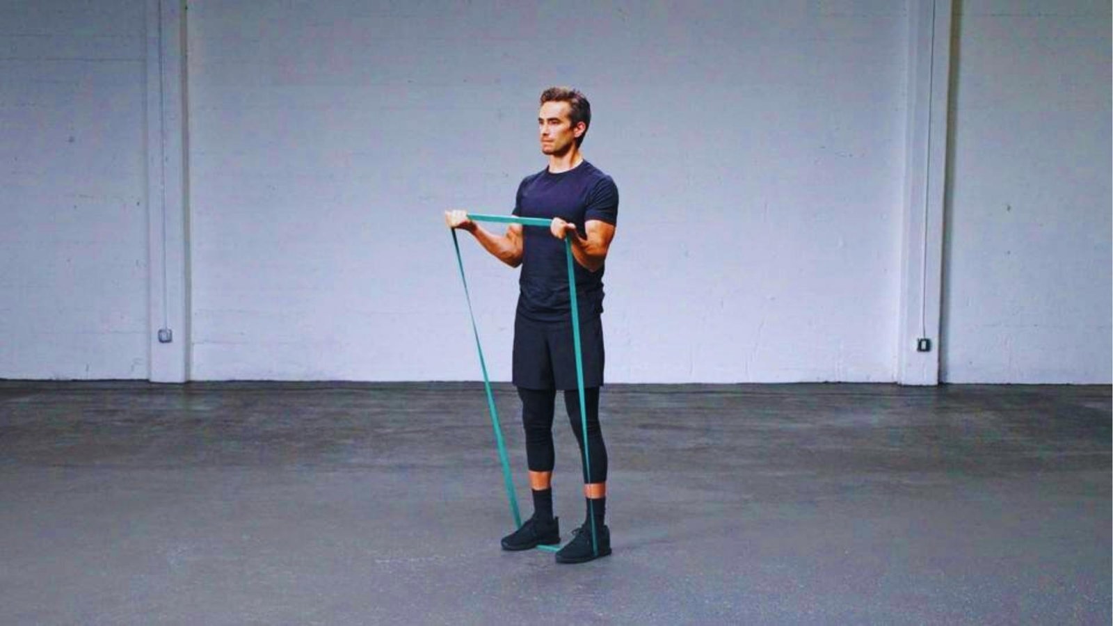 Man doing biceps curl with long green resistance band standing full body exercise for beginners.
