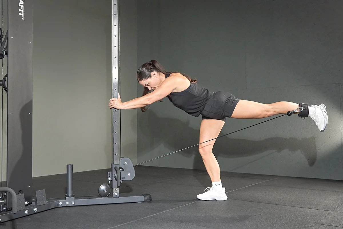 Woman performing cable kickbacks with an ankle strap.