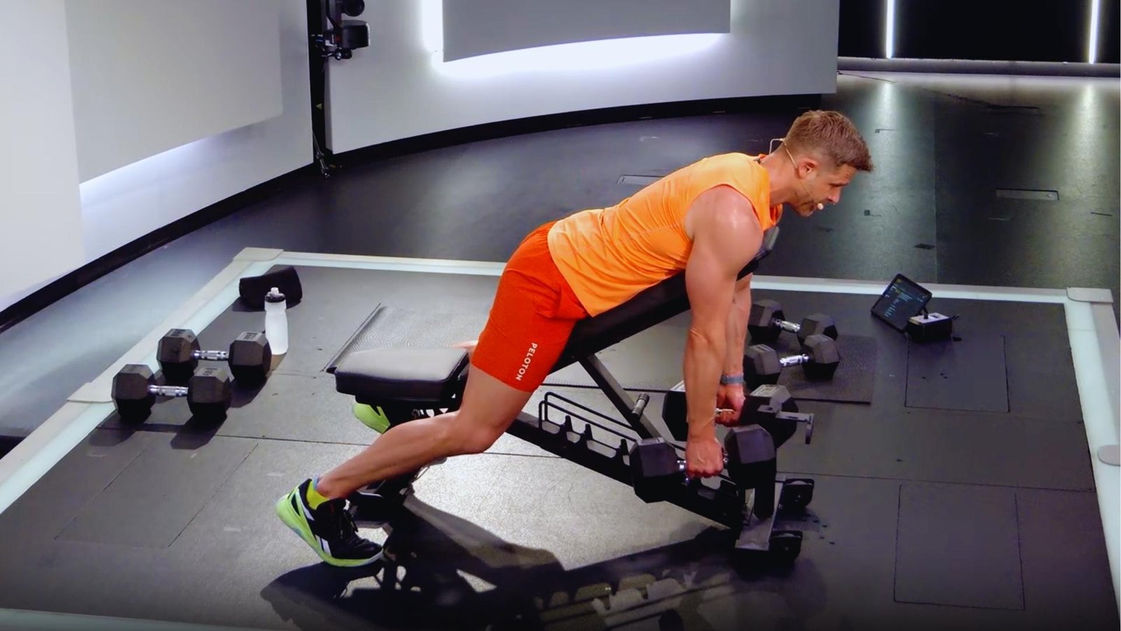 Man performing incline bench dumbbell chest supported row for better back gains in studio gym.