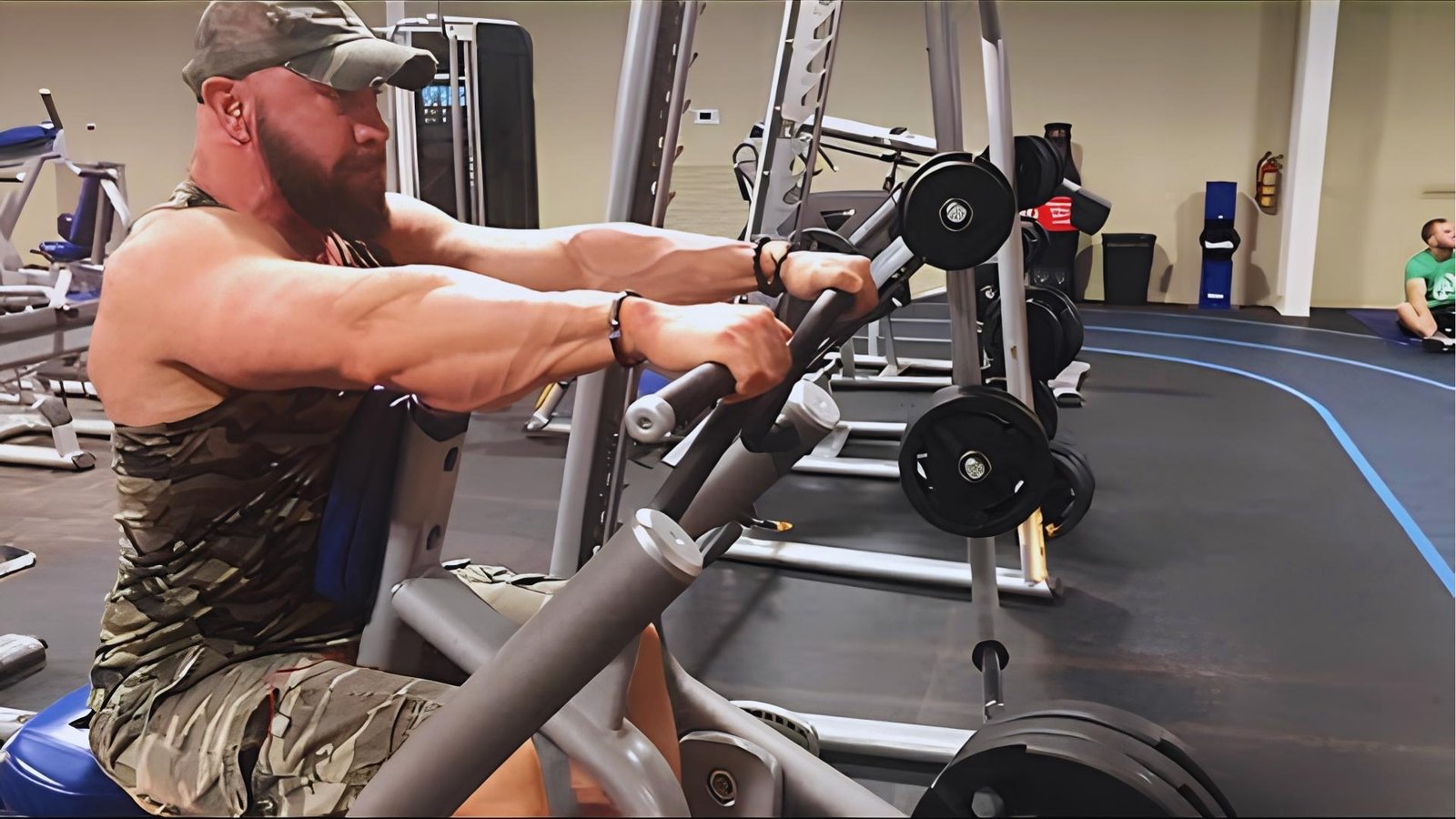 Bearded man in camo doing chest supported row machine exercise for upper back.