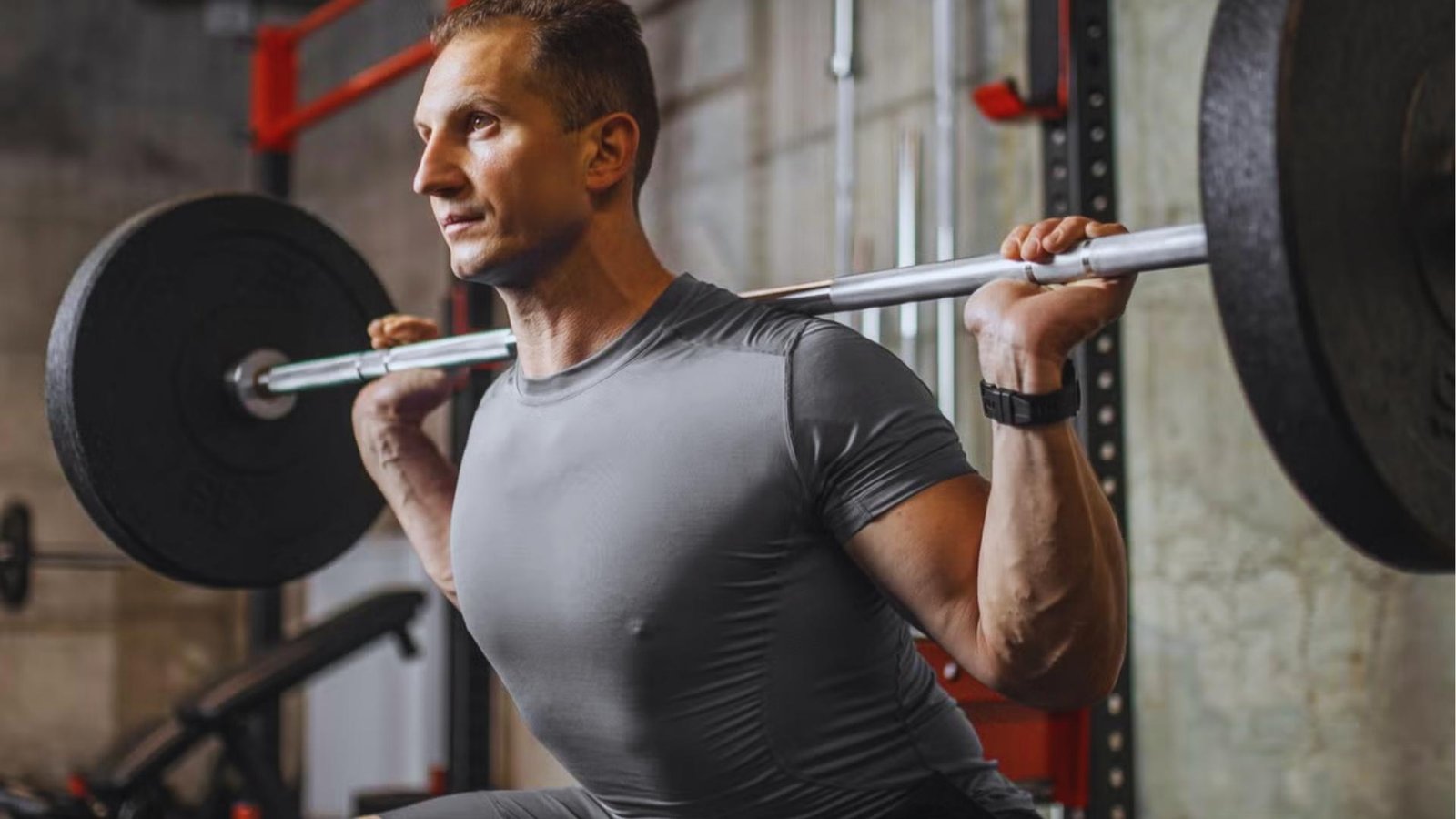 Man performing heavy barbell back squat in gym with proper form to prevent lower back injury.
