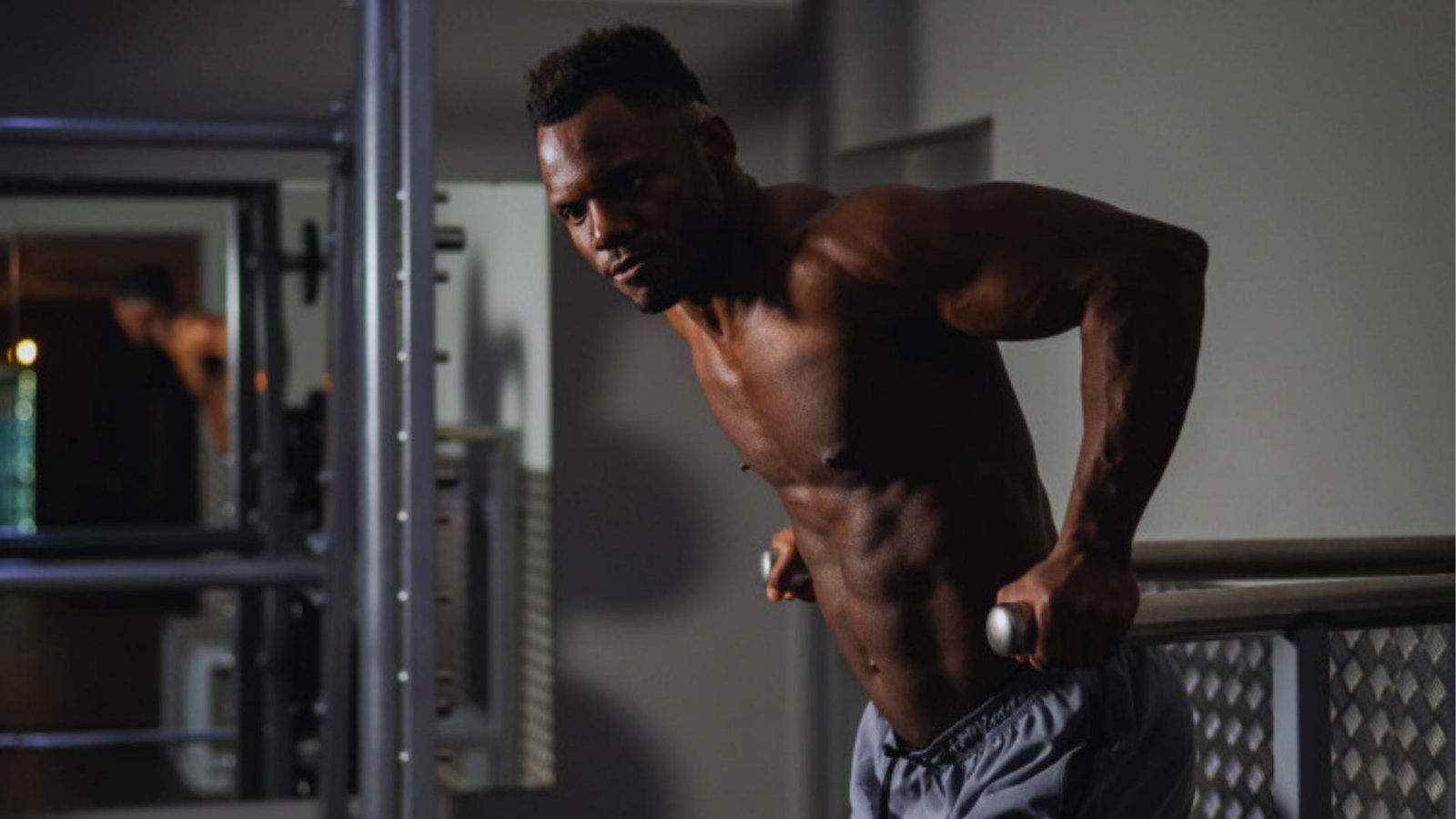 Athlete performing triceps dips on parallel bars in gym, upper body strength workout.