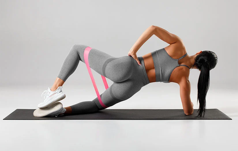 Woman performing clamshell exercise with a resistance band.