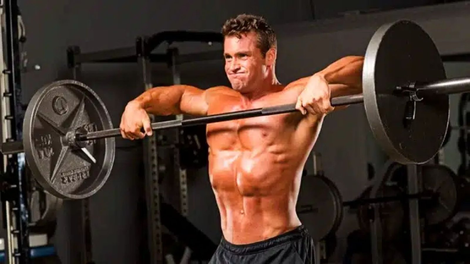 man performing a wide-grip upright row with a barbell to target the medial delts.