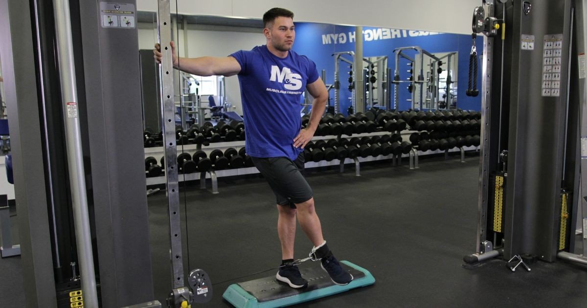 Man performing a controlled cable hip abduction with proper form.
