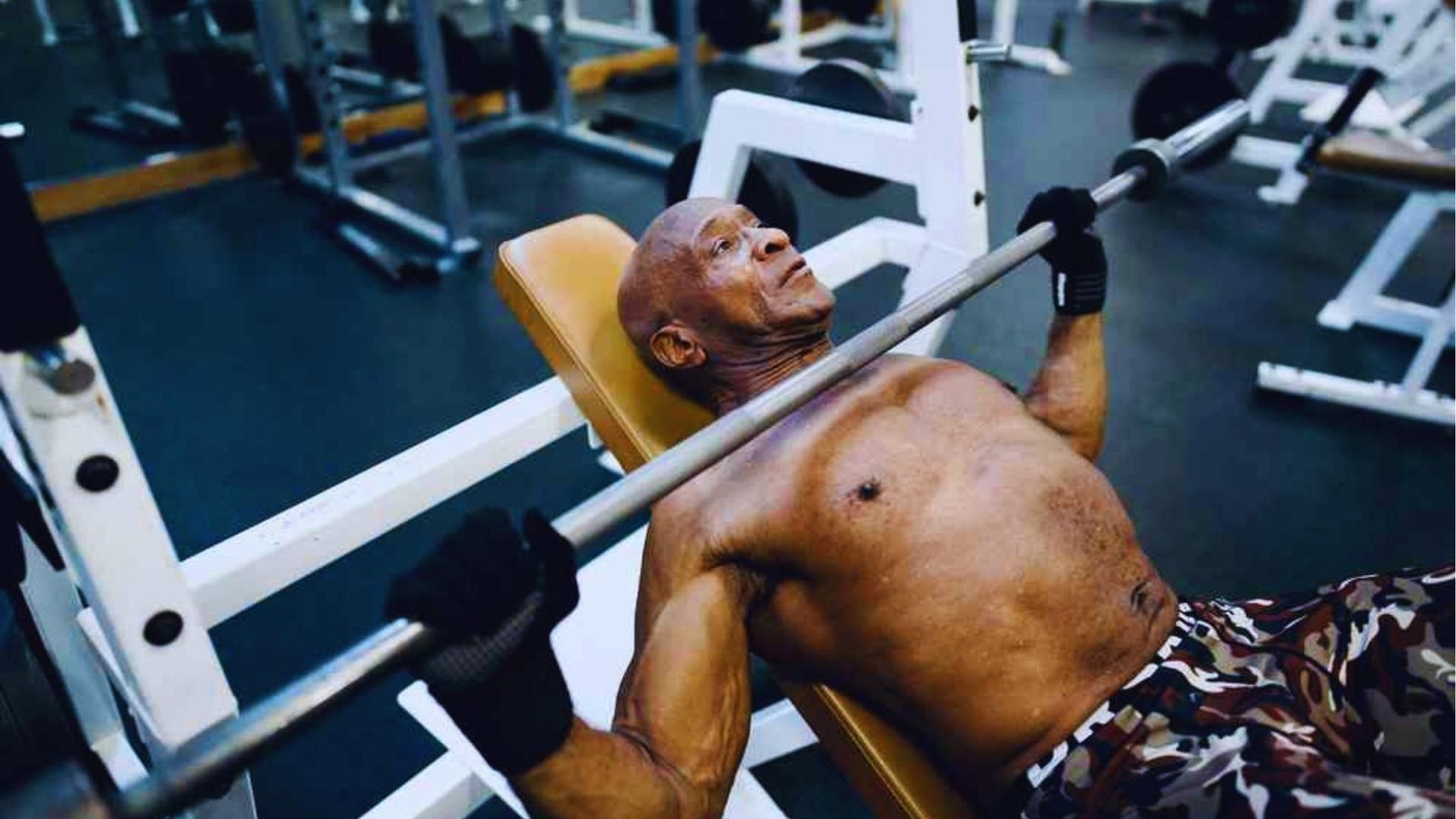 Senior muscular man doing incline barbell bench press with gloves, shoulder pain fix for bench.