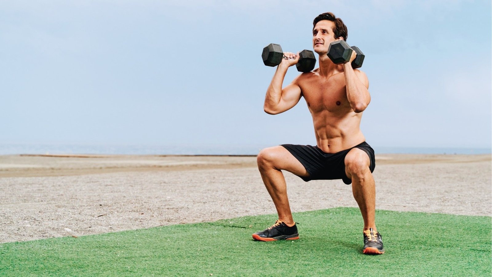 Athlete performing a dumbbell thruster exercise.